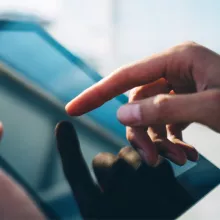 A person holding a tablet, with their finger touching the screen